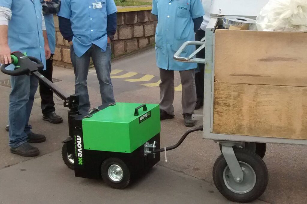 Tractor eléctrico TT2500-S remolcando carga en almacén